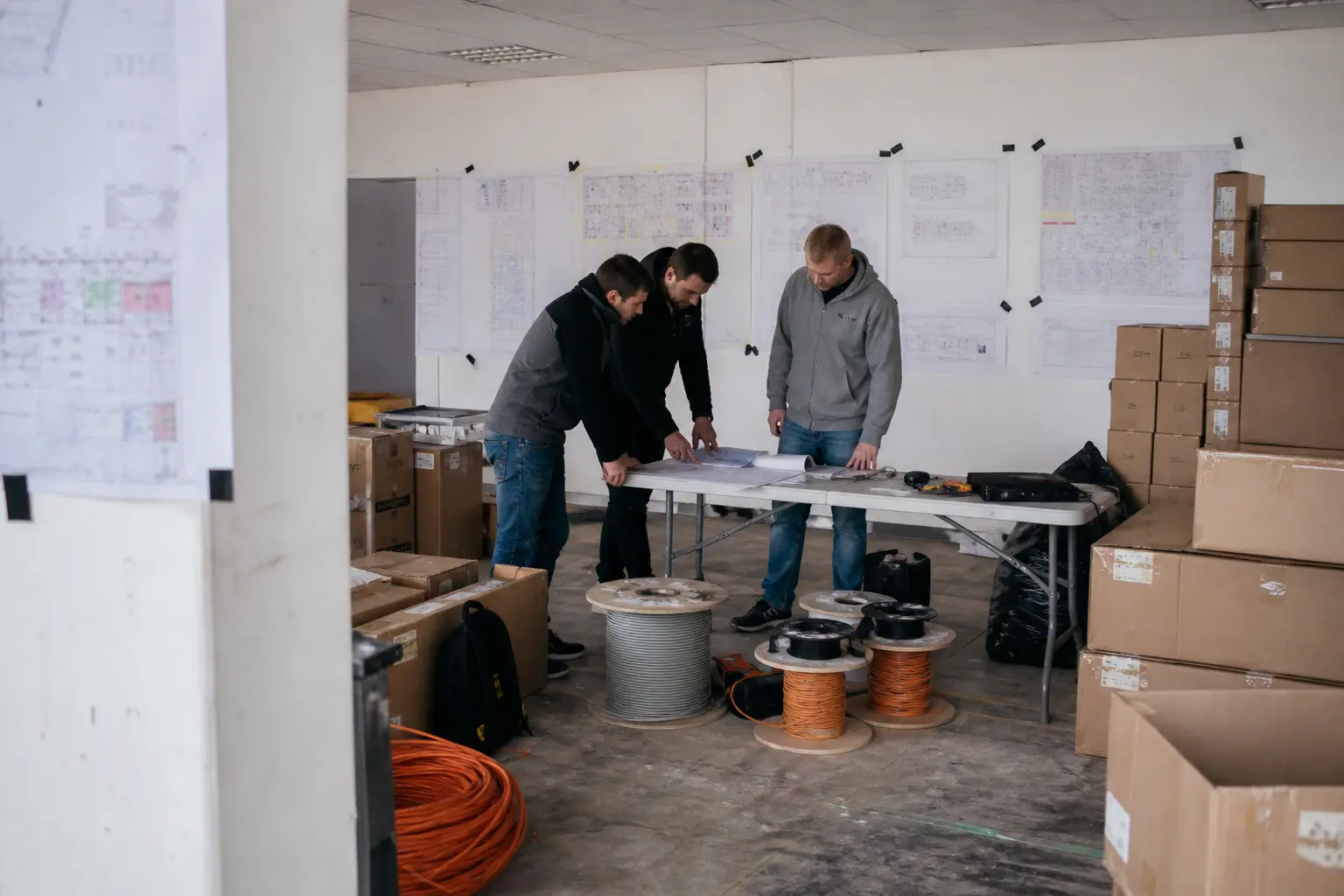 Projektteam plant einen IT-Rollout zwischen Geräten, Kabeln und Bauplänen.