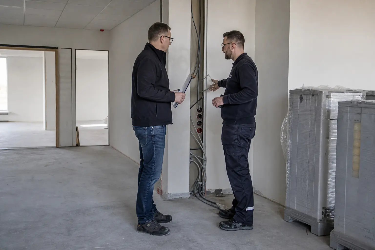 Projektleitung und Techniker stimmen eine Verkabelung auf der Baustelle ab.