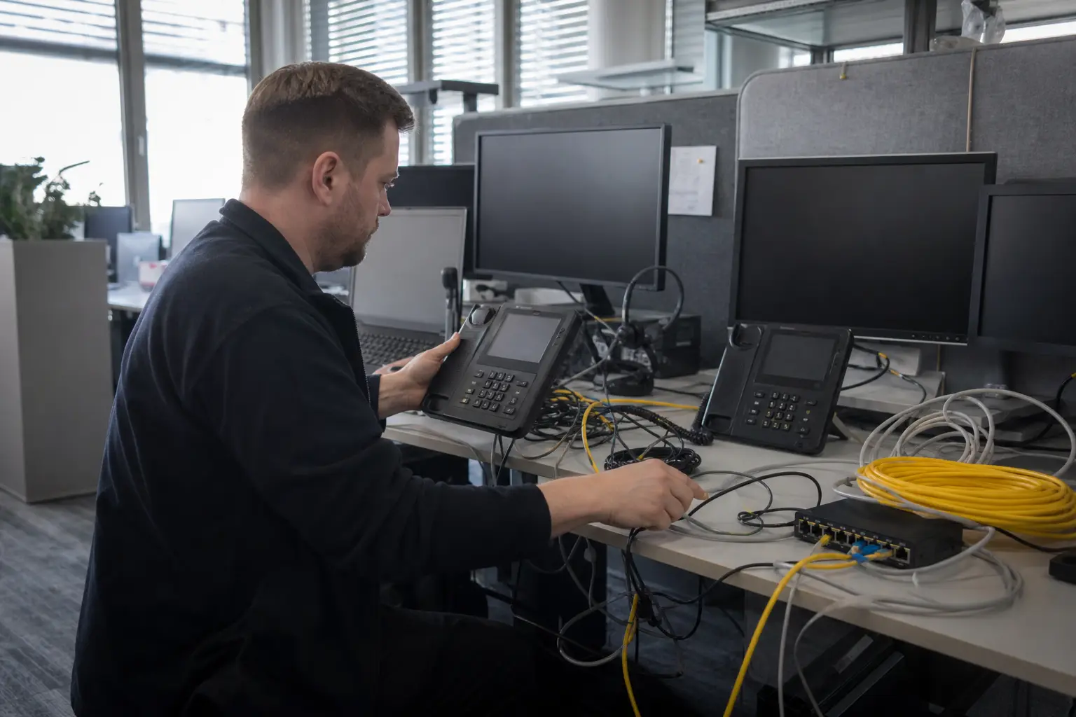 Techniker richtet Tischtelefone, Headsets und Netzwerkanschlüsse ein.